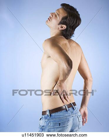A young man holding his back View Large Photo Image Stock Image - A young man holding his back. Fotosearch