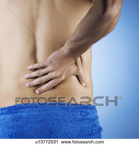 A young man holding his back View Large Photo Image Stock Image - A young man holding his back. Fotosearch