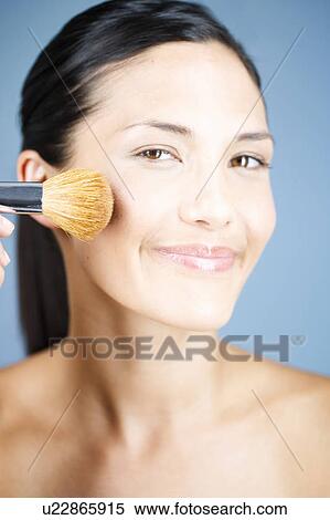 A young woman applying blusher with a brush View Large Photo Image Stock Photography - A young woman applying blusher with a brush. Fotosearch