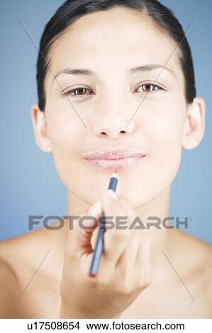 Picture - A young woman applying lip liner. Fotosearch