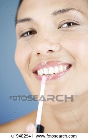 A young woman applying lipgloss View Large Photo Image Stock Image - A young woman applying lipgloss. Fotosearch