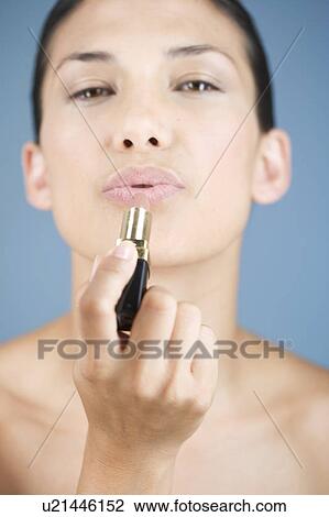 Stock Image - A young woman applying lipstick. Fotosearch