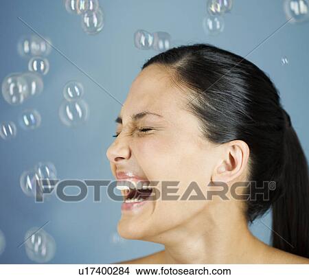 Picture - A young woman blowing bubbles. Fotosearch