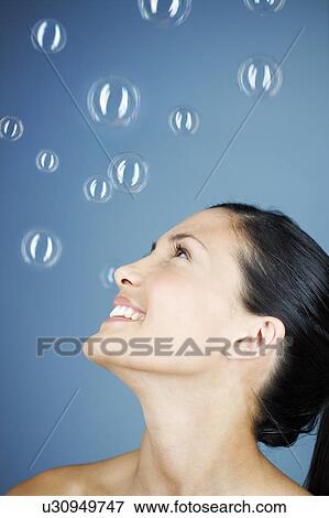 Stock Photo - A young woman blowing bubbles. Fotosearch