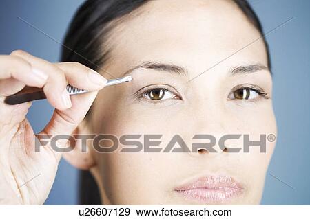 A young woman plucking her eyebrows View Large Photo Image Stock Photo - A young woman plucking her eyebrows. Fotosearch
