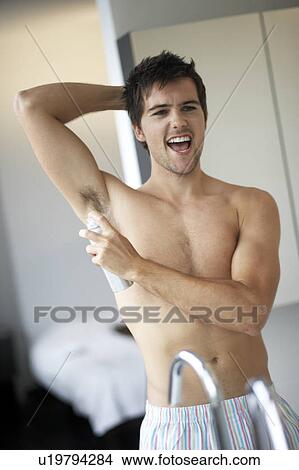 Young man applying de-odorant/anti-perspirant View Large Photo Image Picture - Young man applying de-odorant/anti-perspirant. Fotosearch