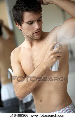 Stock Photograph - Young man applying de-odorant/anti-perspirant. Fotosearch