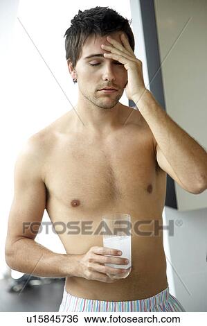 Stock Photograph - Young man drinking a hangover remedy. Fotosearch