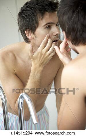 Young man looking at his reflection in a mirror View Large Photo Image Picture - Young man looking at his reflection in a mirror. Fotosearch