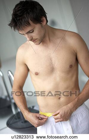 Young man measuring his waist View Large Photo Image Stock Image - Young man measuring his waist. Fotosearch