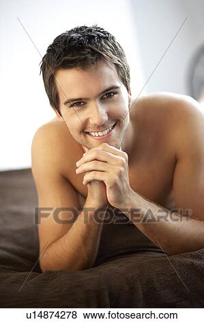 Young man laying on a bed View Large Photo Image Stock Photo - Young man laying on a bed. Fotosearch