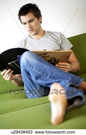 Stock Image - Young man looking at his record collection. Fotosearch
