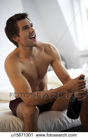 Young man opening a bottle of champagne in the bedroom View Large Photo Image Stock Image - Young man opening a bottle of champagne in the bedroom. Fotosearch