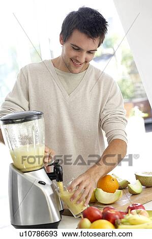 Stock Image - Young man preparing fresh fruit juice. Fotosearch
