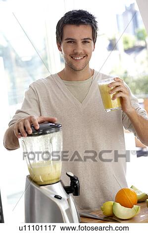 Stock Photo - Young man preparing fresh fruit juice. Fotosearch