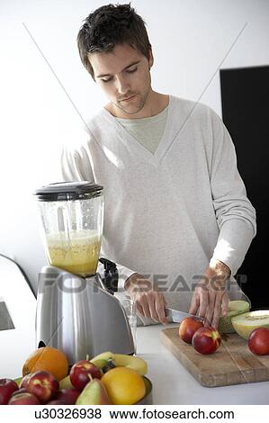 Young man preparing fresh fruit juice View Large Photo Image Stock Photo - Young man preparing fresh fruit juice. Fotosearch