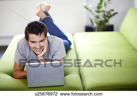Young man with a laptop, laying on a bed View Large Photo Image Stock Image - Young man with a laptop, laying on a bed. Fotosearch