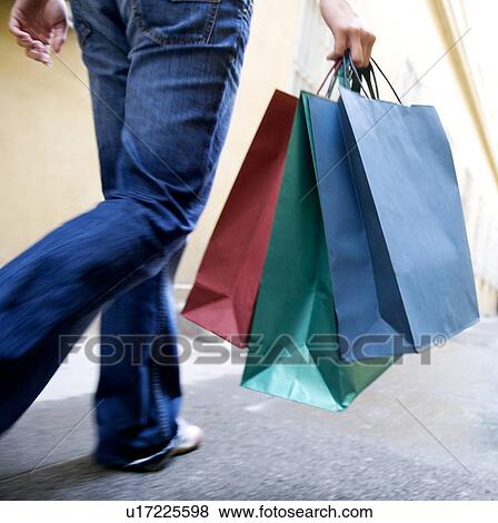 Stock Photo - A person carrying shopping bags. Fotosearch
