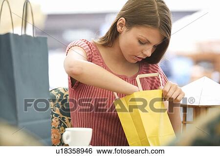 A young woman looking at her purchases View Large Photo Image Stock Photograph - A young woman looking at her purchases. Fotosearch