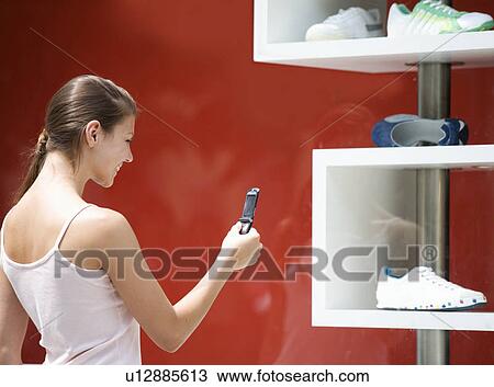 Stock Image - A young woman looking in a shop window. Fotosearch