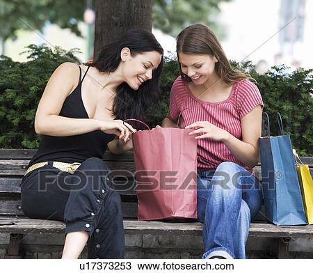 Stock Image - Two young women looking at their purchases. Fotosearch