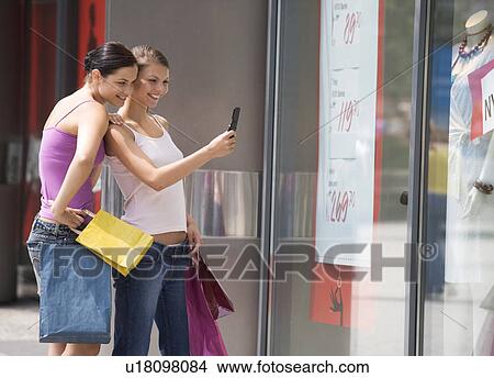 Two young women looking in a shop window View Large Photo Image Picture - Two young women looking in a shop window. Fotosearch