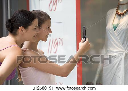 Two young women looking in a shop window View Large Photo Image Stock Image - Two young women looking in a shop window. Fotosearch