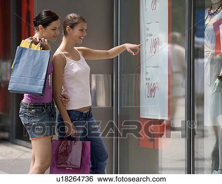Stock Photograph - Two young women looking in a shop window. Fotosearch