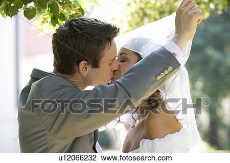 A bride and groom kissing View Large Photo Image Stock Image - A bride and groom kissing. Fotosearch