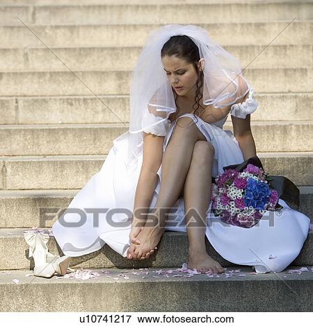 A bride sitting outside the church massaging her feet View Large Photo Image Stock Photo - A bride sitting outside the church massaging her feet. Fotosearch