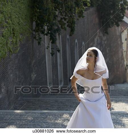 Stock Photograph - A bride walking in a cobbled street. Fotosearch
