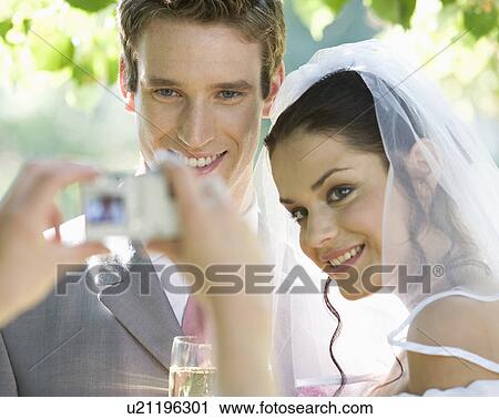 Stock Image - A guest taking a photo of the bride and groom. Fotosearch
