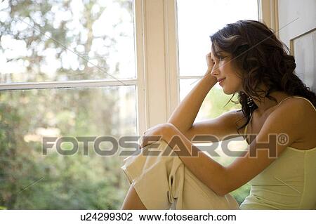 A young woman sitting in a window View Large Photo Image Stock Image - A young woman sitting in a window. Fotosearch