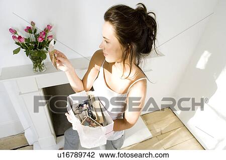Stock Image - A young woman looking at old photographs. Fotosearch