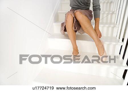 Stock Photo - A young woman putting on shoes. Fotosearch