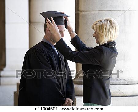Stock Image - A mother checking her graduate son's gown. Fotosearch