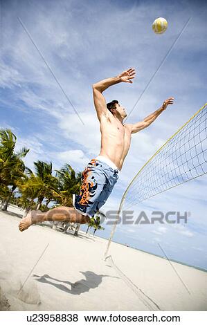 Stock Photo - A young man playing beach volleyball. Fotosearch