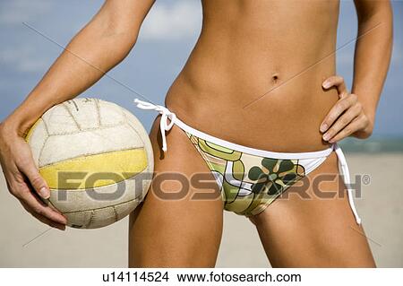 A young woman on a beach holding a ball View Large Photo Image Picture - A young woman on a beach holding a ball. Fotosearch