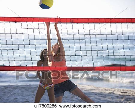 Stock Photograph - Two women playing beach volleyball. Fotosearch