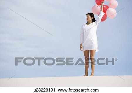 Stock Image - A woman holding a bunch of balloons. Fotosearch