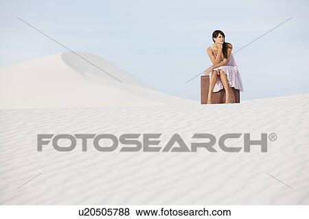 A young woman sitting on a suitcase in the desert View Large Photo Image Stock Photo - A young woman sitting on a suitcase in the desert. Fotosearch