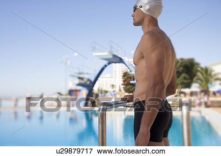 A young man standing by a swimming pool View Large Photo Image Stock Photo - A young man standing by a swimming pool. Fotosearch