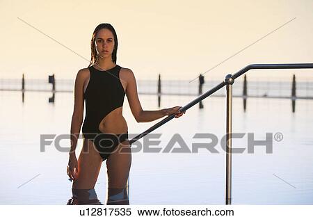 Stock Photography - A young woman standing by a swimming pool. Fotosearch