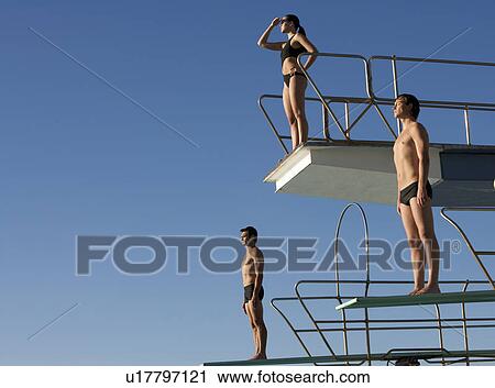 Stock Image - Three divers standing on diving boards. Fotosearch