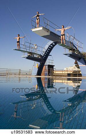 Stock Image - Three divers standing on diving boards. Fotosearch
