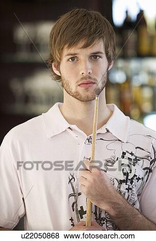 Stock Photo - Portrait of a young man playing pool. Fotosearch