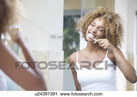 Stock Image - A young woman brushing her teeth. Fotosearch