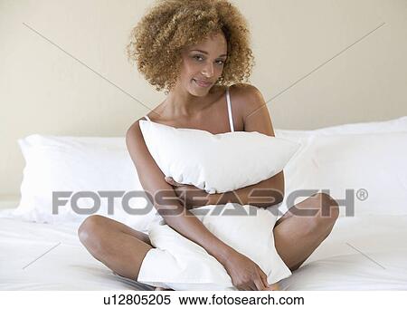 Stock Photography - A young woman hugging a pillow. Fotosearch