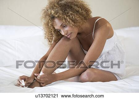 Stock Image - A young woman painting her nails. Fotosearch