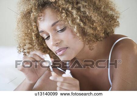 A young woman painting her nails View Large Photo Image Stock Photo - A young woman painting her nails. Fotosearch